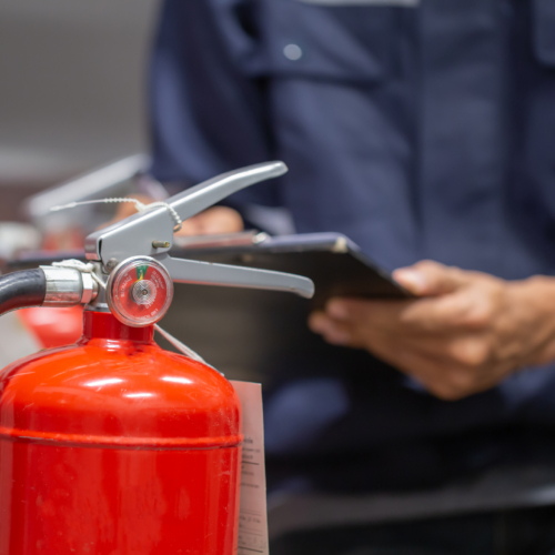 a fire extinguisher holding a clipboard next to a fire exting